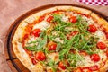 Italian Pizza with tomatoes, mozzarella cheese and arugula on wooden cutting board. Royalty Free Stock Photo
