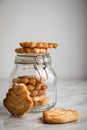 Italian puff pastry fan wavers cookies biscuits with preserving glass jar on marble table background Royalty Free Stock Photo