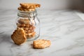 Italian puff pastry fan wavers cookies biscuits with preserving glass jar on marble table background Royalty Free Stock Photo