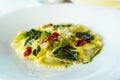Italian ravioli pasta with basil, spinach, sun-dried tomatoes, pine nuts and cheese in a white plate. Traditional Royalty Free Stock Photo