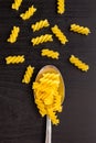 italian raw pasta spiral fusilli dry on a metallic spoon and an black table Royalty Free Stock Photo