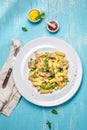 Italian recipe Pasta tortilloni with green pea, mint leaves, cheece, smoked bacon and cheese. Top view, blue background.