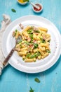 Italian recipe Pasta tortilloni with green pea, mint leaves, cheece, smoked bacon and cheese. Top view, blue background.
