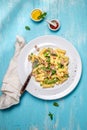 Italian recipe Pasta tortilloni with green pea, mint leaves, cheece, smoked bacon and cheese. Top view, blue background.