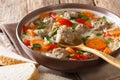 Italian soup with pasta orzo, meatballs and vegetables close-up in a plate served with bread. horizontal