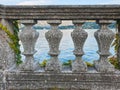 Italian stone balustrade illuminated by sun rays and water in the background Royalty Free Stock Photo