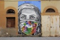 Italian street art graffiti mural woman face in medical mask. Stornara, Puglia, Italy