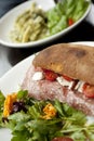 Italian Style Ciabatta with Salami, Mozzarella, Tomatoes and Salad and Pasta Dish in background