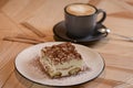 Italian stylish dessert, a piece of Tiramisu cake on a white plate and a cup of black coffee in a black cup on a table Royalty Free Stock Photo