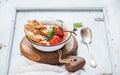 Italian tomato, garlic and basil soup Pappa al Pomodoro in metal bowl with bread on rustic wooden board over light blue Royalty Free Stock Photo