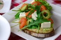 Italian traditional bruschetta with tomato basil and green olives. Served on a white plate over red plaid tablecloth.