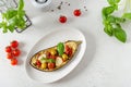 Italian traditional dish with eggplant, tomatoes, olives, mozzarella and basil. Baked aubergine stuffed with vegetables on a white Royalty Free Stock Photo