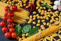Italian traditional food, spices and ingredients for cooking as basil, cherry tomatoes, chili pepper, garlic and various pasta Royalty Free Stock Photo
