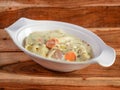 Italian veg pasta topped with a white creamy sauce and basil served in a white plate on a rustic wooden table, selective focus Royalty Free Stock Photo