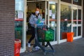 Grocery store and shopping during coronavirus lockdown in italy: man with protective mask exiting store with cart stocked of food