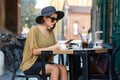 Elegant Italian woman with hat and glasses writes a message with her smartphone