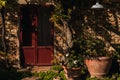 Italy, classic old Tuscan farmhouse red door with flowers and plants inside pots