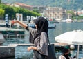woman with black burka making selfie with lake Como and boat background