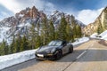 Italy, The Dolomites, Canazei, The expensive luxury sport car a stops on the twisted road against snow-covered mountains