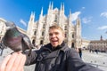 Italy, excursion and travel concept - funny guy taking selfie with pigeons in front of cathedral Duomo in Milan Royalty Free Stock Photo