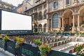 Open air auditorium with large screen among the buildings of classical architecture in the center of Milan