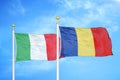 Italy and Romania two flags on flagpoles and blue cloudy sky