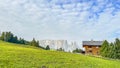 In Italy\'s Dolomites, an isolated wooden house nestles on a green hill