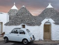 Italy. Traditional white washed trulli house with white Fiat vintage cinquecento 500 car parked in front, in Alberobello Puglia Royalty Free Stock Photo