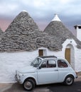 Italy. Traditional white washed trulli house with white Fiat vintage cinquecento 500 car parked in front, in Alberobello Puglia Royalty Free Stock Photo