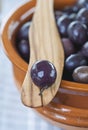 Italy, Tuscany, Magliano, Close up of black olives in bowl with one olive on wooden spatula Royalty Free Stock Photo