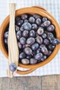 Italy, Tuscany, Magliano, Close up of black olives in bowl with one olive on wooden spatula Royalty Free Stock Photo