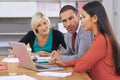 Itd be good to hear your thoughts on this...Three coworkers brainstorming around a laptop.