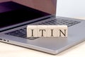 ITIN word on wooden block on laptop, business concept