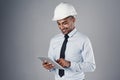 Its all coming together now. a well-dressed civil engineer using his tablet while standing in the studio. Royalty Free Stock Photo