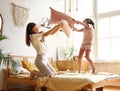 Its a battle. Excited happy older and younger sister fighting with pillows in bedroom, laughing and having fun together Royalty Free Stock Photo