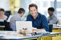 Its been a great ride to the top. Portrait of a designer sitting at his desk working on a laptop with colleagues in the