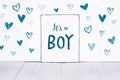 It`s a boy new born baby text on sign board with cute little blue hearts on white background