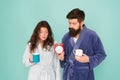 Its coffee time. Every morning begins with coffee. Couple in bathrobes with mugs. Man with beard and sleepy woman enjoy