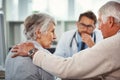 Its a difficult time for them. a senior man consoling his wife during a consultation with a doctor in a clinic. Royalty Free Stock Photo