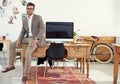 Its a great place to work. Portrait of a casually-dressed young man sitting on his desk in an office. Royalty Free Stock Photo