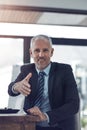 Its great to meet you. Portrait of a mature businessman offering you his hand while stting in his office. Royalty Free Stock Photo