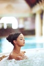 Its hard not to be relaxed in a hot tub. an attractive young woman relaxing in an indoor jacuzzi at a beauty spa.