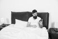 Its hard to get out of bed. Bearded man check time with alarm clock. Sleep time. Sleep and wake routine. Bed time Royalty Free Stock Photo