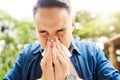 Its hayfever season. a young man blowing his nose while out in the park. Royalty Free Stock Photo