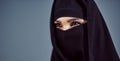 Its in her eyes. Studio shot of a young arabic woman wearing a burka against a gray background.