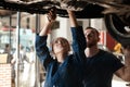 Its only her first day but shes already doing great. two mechanics working together under a lifted car. Royalty Free Stock Photo