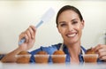 Its the icing on the cake. A happy young woman about to apply frosting to her freshly-baked batch of cupcakes. Royalty Free Stock Photo