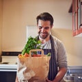 Its a meal in the making. a happy young man holding a bag of groceries in his kitchen at home. Royalty Free Stock Photo