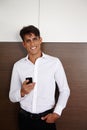 Its always nice to get feedback from clients. Portrait of a handsome young businessman standing indoors with his mobile Royalty Free Stock Photo