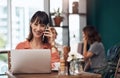 Its so nice to hear from you. An attractive middle aged woman talking on her cellphone while working on a laptop inside Royalty Free Stock Photo